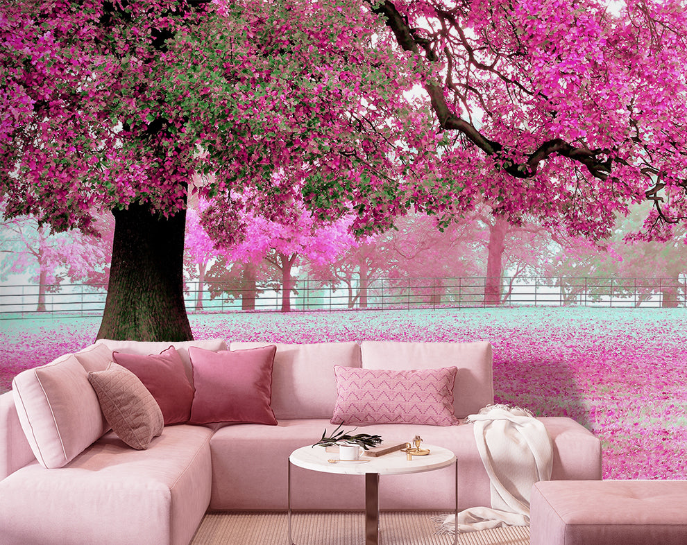 Pink sectional sofa with decorative pillows in a room with cherry blossom wall mural.