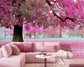 Pink sectional sofa with decorative pillows in a room with cherry blossom wall mural.